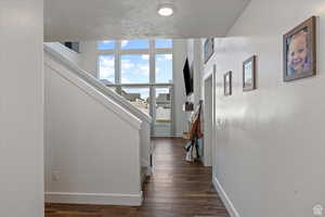 Corridor with baseboards, dark wood-style floors, and stairway