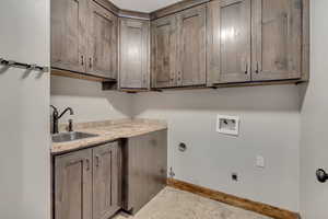 Laundry area featuring hookup for a gas dryer, hookup for a washing machine, cabinet space, hookup for an electric dryer, and baseboards