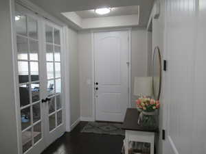 Doorway to outside with baseboards, french doors, dark wood-type flooring, and a tray ceiling