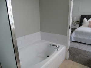 Ensuite bathroom featuring a bath and wood finished floors