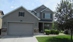 Craftsman inspired home featuring stone siding, driveway, and stucco siding