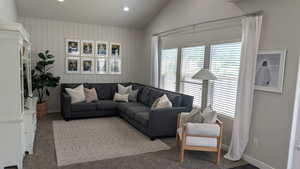 Living area with plenty of natural light, lofted ceiling, carpet flooring, recessed lighting, and baseboards