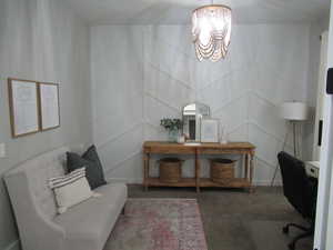 Carpeted office featuring a chandelier and a decorative wall