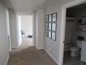 Hallway with carpet flooring and baseboards