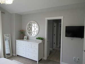 Bedroom with baseboards, light colored carpet, and a chandelier