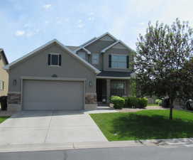 Craftsman-style house with stone siding, driveway, stucco siding, and a front yard