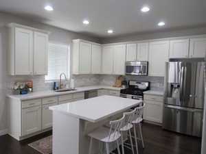 Kitchen with appliances with stainless steel finishes, a sink, dark wood finished floors, recessed lighting, and backsplash