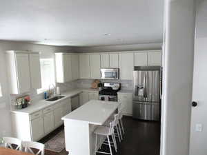 Kitchen with stainless steel appliances, a sink, tasteful backsplash, a center island, and a kitchen bar