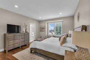 Bedroom with dark wood finished floors, recessed lighting, ensuite bath, and baseboards