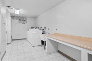Washroom with washing machine and clothes dryer, a sink, light tile patterned flooring, and an office area