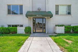 Doorway to property featuring brick siding and a lawn