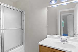 Full bath with vanity and bath / shower combo with glass door