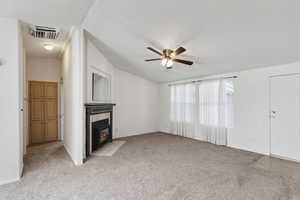 Unfurnished living room with light carpet, ceiling fan, a fireplace, and baseboards