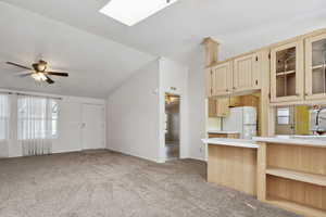 Kitchen with freestanding refrigerator, tile counters, ceiling fan, light colored carpet, and vaulted ceiling