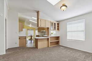 Kitchen with white appliances, open shelves, vaulted ceiling, under cabinet range hood, and light brown cabinets