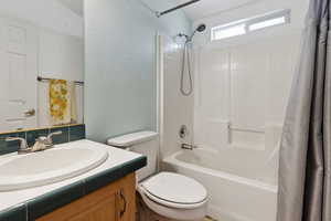 Bathroom featuring shower / bath combo, vanity, toilet, and a textured wall
