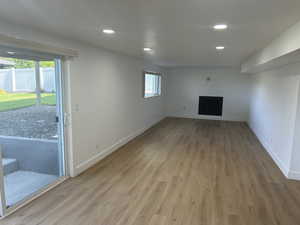 Unfurnished living room featuring light wood finished floors, baseboards, a fireplace, and recessed lighting