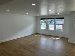 Unfurnished room featuring baseboards, recessed lighting, wood finished floors, and a textured ceiling