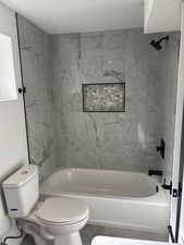 Bathroom with toilet, shower / washtub combination, and a textured ceiling