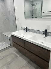 Bathroom featuring double vanity and a marble finish shower