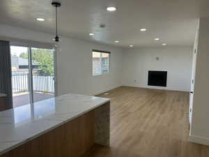 Unfurnished living room featuring light wood-style floors, recessed lighting, baseboards, and a fireplace