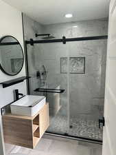 Full bathroom featuring a marble finish shower and vanity