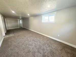 Below grade area featuring a textured ceiling, baseboards, carpet floors, and recessed lighting