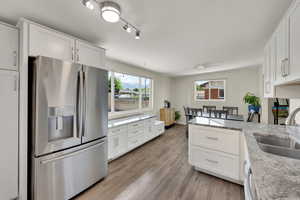 Kitchen featuring stainless steel fridge with ice dispenser, a sink, a peninsula, and white cabinets