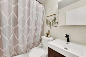 Bathroom with vanity, toilet, and curtained shower