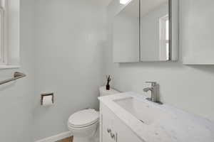 Half bathroom with vanity, toilet, and baseboards