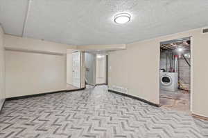 Finished basement with washer / clothes dryer, baseboards, and a textured ceiling