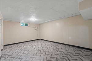Basement featuring a textured ceiling and baseboards