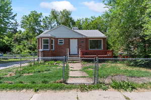 Bungalow-style home featuring a gate, a fenced front yard, and brick siding