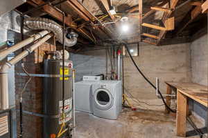 Unfinished basement featuring water heater and washer and clothes dryer