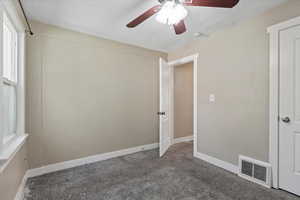 Empty room featuring ceiling fan, a textured ceiling, carpet floors, and baseboards