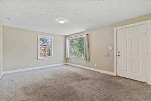 Carpeted spare room with baseboards and a textured ceiling