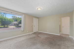 Unfurnished room featuring arched walkways, a textured ceiling, carpet flooring, and baseboards