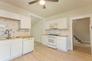 Kitchen featuring white appliances, a sink, wooden counters, and tasteful backsplash