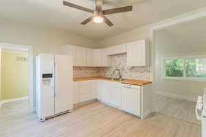 Kitchen with white appliances, a sink, wood counters, backsplash, and ceiling fan