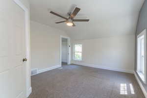 Empty room featuring lofted ceiling, ceiling fan, carpet flooring, and baseboards