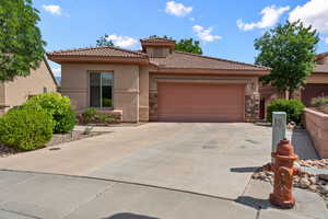 Mediterranean / spanish house featuring stucco siding, a tiled roof, concrete driveway, and stone siding