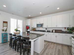 Kitchen with stainless steel appliances, a sink, light wood-style floors, white cabinets, and recessed lighting