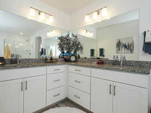 Bathroom featuring a shower stall, double vanity, and wood finished floors