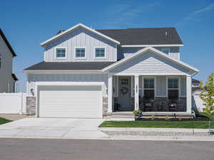 Craftsman inspired home with board and batten siding, covered porch, a shingled roof, and driveway