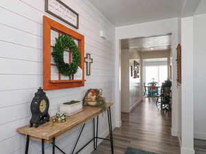 Hallway featuring wood finished floors, shiplap walls, baseboards, and a textured ceiling