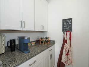 Butler Pantry off of Kitchen with white cabinetry and dark stone countertops