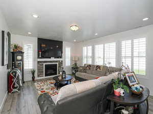 Family room featuring baseboards, wood finished floors, a glass covered fireplace, and recessed lighting