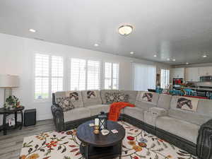 Living area with light wood-style floors, baseboards, and recessed lighting