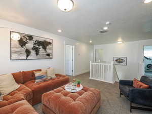 Carpeted living area featuring a textured ceiling, recessed lighting, and baseboards