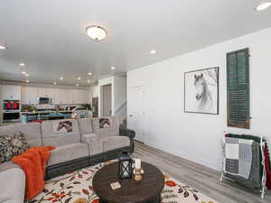 Living room with light wood-type flooring, recessed lighting, stairway, and baseboards